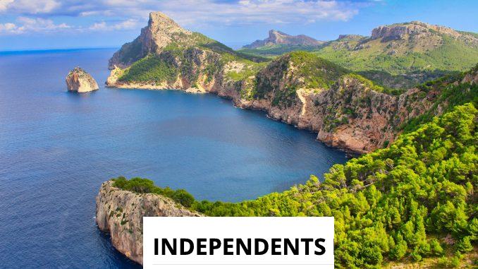 green and brown mountain beside blue sea under blue sky during daytime