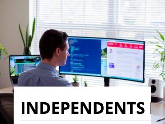 man in gray dress shirt sitting on chair in front of computer monitor