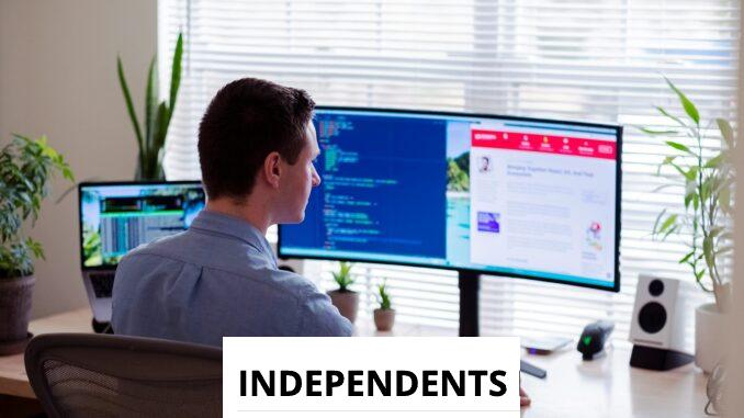 man in gray dress shirt sitting on chair in front of computer monitor